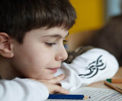 Im Klassenraum: Ein Kind schaut auf seine Schulaufgaben
