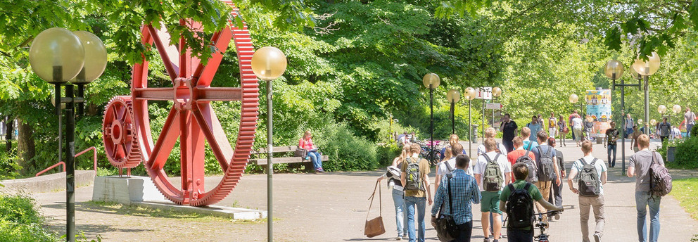 Students on the North Campus Students walking across Campus Nord. In The background there is a red sculpture of large gears.