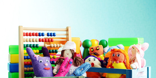 Spielerisches Lernen Bunte Handpuppen und Quietscheentchen vor einem Rechenschieber und Bauklötzen.