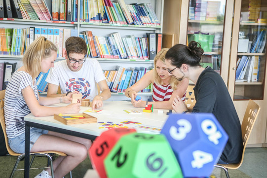 People with cubes in workshop Four people are sitting at a table building something with dices.