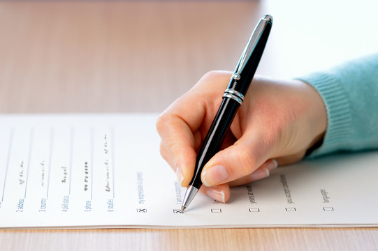 Survey A hand holding a pen fills out a survey questionnaire.